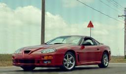 Car photo with distracting signs and poles in background.